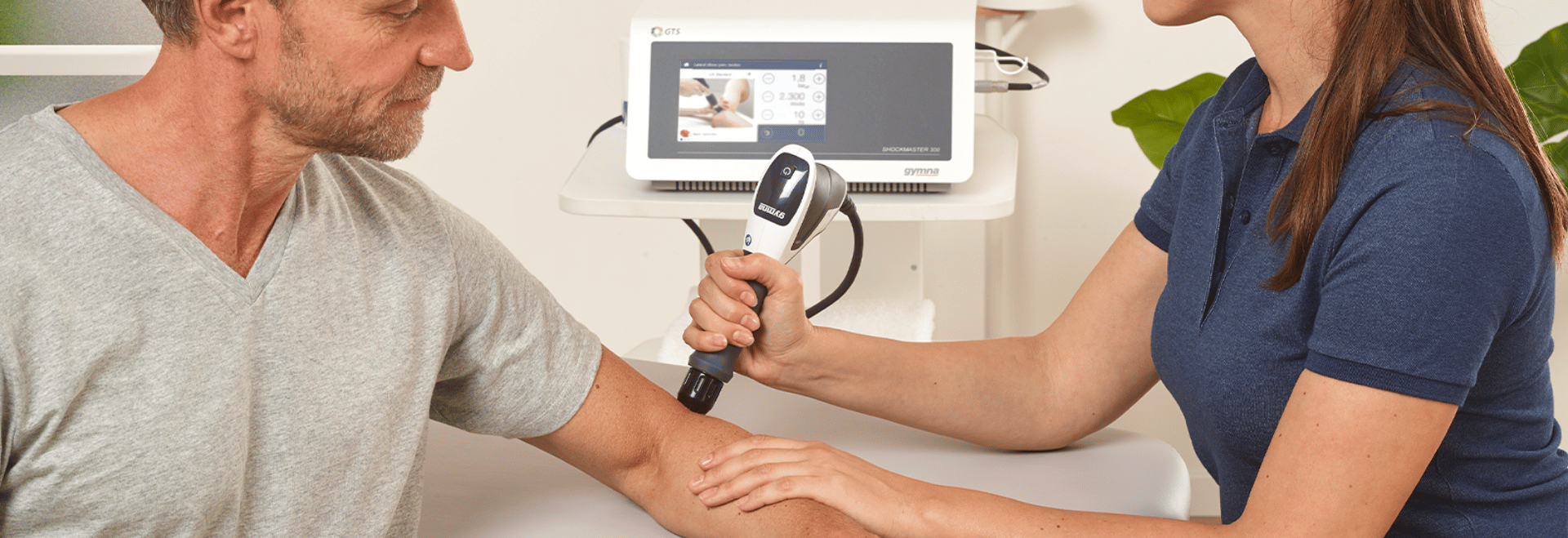 Un physiothérapeute traitant le bras d'un patient à l'aide d'une thérapie par ondes de choc.